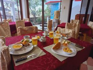 uma mesa com pratos de comida e copos de sumo de laranja em Hotel Sula Sula em Puerto Villamil