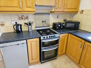 a kitchen with wooden cabinets and a stove top oven at Brunswick Park Shared House in Wednesbury