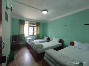 a room with three beds and a window at Hotel Mount Paradise in Nagarkot