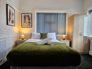 Brunswick Park Shared House في وينزبيري: غرفة نوم بسرير اخضر كبير بها مصباحين