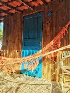 a blue door on a wooden house with a net at Pousada Roy Bonete in Ilhabela