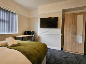 a hotel room with a bed and a flat screen tv at Brunswick Park Shared House in Wednesbury