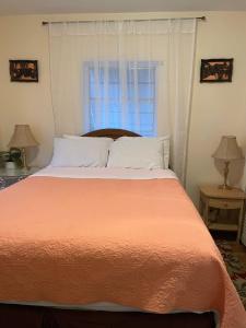 a bed with an orange comforter and a window at House next to the golf course in Plantation