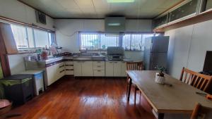 a kitchen with a wooden table and a wooden floor at 一棟貸し 喜瀬しーばなゲストハウス -Traditional House Rent- in Amami