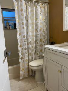 a bathroom with a toilet and a shower curtain at House next to the golf course in Plantation