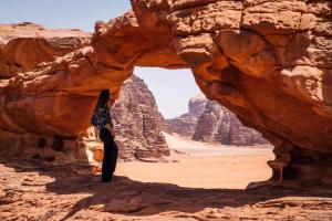 a person standing under a rock arch in the desert at Bedouin bunch camp in Wadi Rum