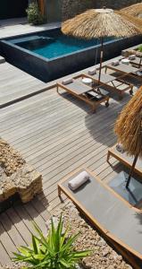 une terrasse avec des chaises longues et une piscine dans l'établissement Hôtel Les Suites Du Maquis, à Bonifacio