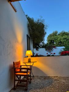 a table with a lamp and a chair next to a wall at Two Olive Trees in Spetses