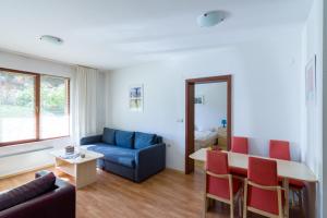 a living room with a blue couch and red chairs at Todorka Apartments in Bansko in Bansko
