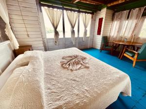 - une chambre avec un lit blanc dans une pièce dotée de fenêtres dans l'établissement HOTEL BACKPACKERS RIO DULCE, à Rio Dulce