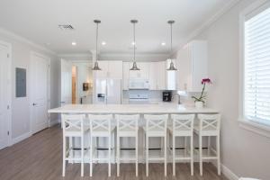 a white kitchen with a large white island with stools at Isla Key Lychee - Waterfront Boutique Resort, Island Paradise, Prime Location in Islamorada