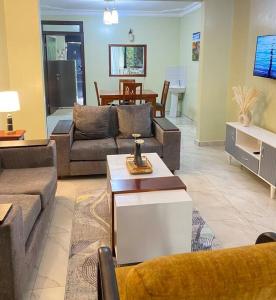 a living room with couches and a dining room at Homie flat with airport view in Entebbe