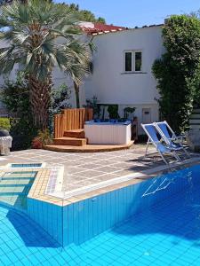 - une piscine avec 2 chaises et une maison dans l'établissement Villa Cinque Pini, à Ischia