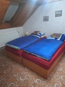 a bedroom with a large bed with blue sheets at Penzion Krušnohorka in Tatrovice