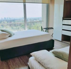 Duas camas num quarto com uma janela grande em Departamento en Puebla (en torre Artema- zona Angelópolis) em Puebla