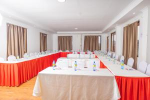 una fila di tavoli in una stanza con sedie rosse e bianche di Paleo Hotel and Spa a Thika