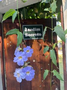 um sinal que diz jardim sectorato ao lado de flores azuis em Jardim Secreto - Itaipava em Itaipava