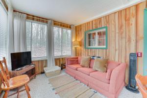 ein Wohnzimmer mit einem rosa Sofa und einem TV in der Unterkunft Roscommon Cabin Less Than Half-Mi to Higgins Lake! in Roscommon
