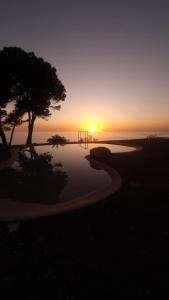 a sunset over the ocean with a tree and a playground at Villa Elvira Country House in Belvedere Marittimo