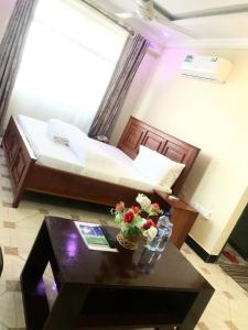 坦噶的住宿－Mbazi Hotel，一间房间,里面设有一张床和一张鲜花桌