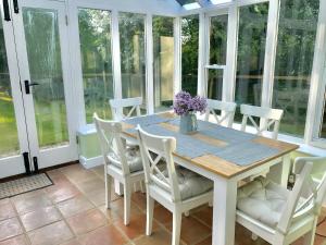 a dining room with a table and white chairs at Pond Cottage in Shaftesbury