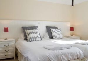 two beds with white sheets and pillows in a room at Pond Cottage in Shaftesbury