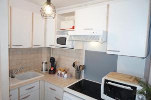 a small kitchen with white cabinets and a sink at Le 33 Cour Normande - Appartement 2 chambres - 2 à 4 personnes - coeur Cabourg in Cabourg