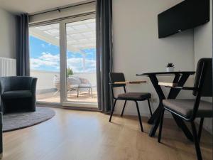 a living room with a table and chairs and a balcony at Penthouse Apartment in Kehl in Kehl am Rhein