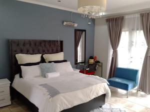 1 dormitorio con 1 cama grande y 1 silla azul en South Serene Guest House, en Midrand