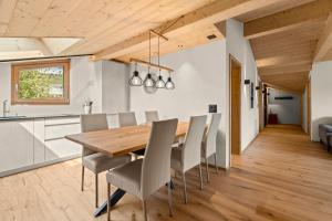 eine Küche und ein Esszimmer mit einem Holztisch und Stühlen in der Unterkunft Stilvolle 4.5 Zimmer Wohnung nahe der Talstation in Vella