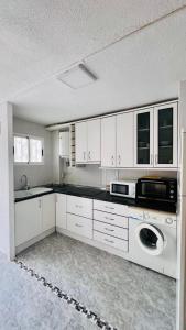 a kitchen with white cabinets and a washer and dryer at Apartamento Pedro in Benidorm