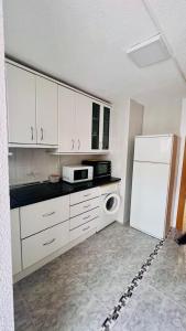 a kitchen with white cabinets and a white refrigerator at Apartamento Pedro in Benidorm