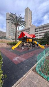 a playground with a yellow slide in a park at Apartamento Pedro in Benidorm