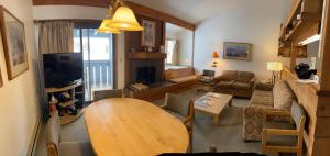 Jackson Hole Vacation Condominiums في ويلسون: غرفة معيشة مع طاولة وغرفة معيشة مع موقد