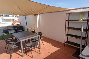 un patio con tavolo, sedie e tenda di Apartamento con terraza 2 hab. ad Alcalá la Real
