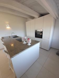 a kitchen with white cabinets and a granite counter top at Villa Ginepro in Olbia