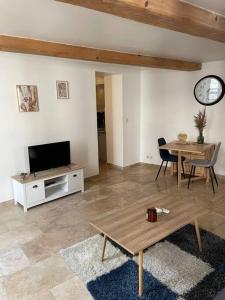 ein Wohnzimmer mit einem TV und einem Tisch in der Unterkunft Appartement à 10 min de St Rémy in Noves