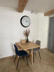 ein Esszimmer mit einem Tisch und einer Uhr an der Wand in der Unterkunft Appartement à 10 min de St Rémy in Noves