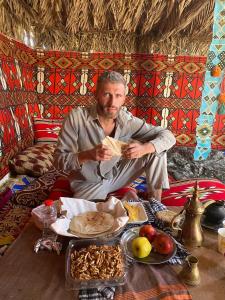 un homme assis à une table avec une assiette de nourriture dans l'établissement Private transportation, à Assouan