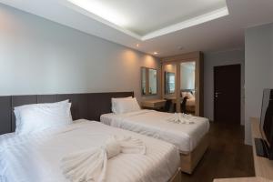 a bedroom with two beds with white sheets at Tisha Hotel in Bang Bo