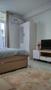 Schlafzimmer mit einem Bett, einem TV und einem Teppich in der Unterkunft Saekyung 956 Condominium in Lo-oc