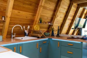a kitchen with blue cabinets and a sink and wooden ceilings at Sunny A Frame in National Park Fruska Gora - Vrdnik in Vrdnik