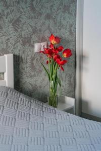 een vaas met rode bloemen op een bed bij Бірюзова студія, Південний вокзал 5 хвилин in Charkov