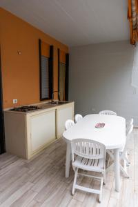 uma cozinha com uma mesa branca e cadeiras brancas em Paradiso Esotico em Torre a Mare