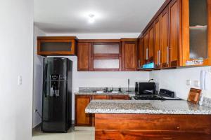 La cuisine est équipée d'un réfrigérateur noir et de placards en bois. dans l'établissement luxurious 3 bedroom apt w pool, à Santiago de los Caballeros
