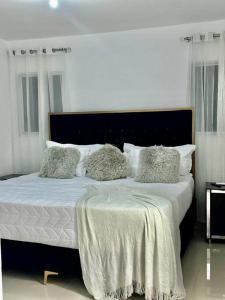 - une chambre avec un lit doté de draps et d'oreillers blancs dans l'établissement luxurious 3 bedroom apt w pool, à Santiago de los Caballeros