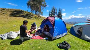 a family sitting in front of a tent at mountain view willcacocha lodge in Huaraz