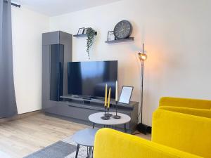 a living room with a yellow couch and a tv at Yellow&Black NEU Designer Apartment Bielefeld City WLAN kostenloser Parkplatz in Bielefeld