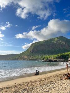 a group of people on a beach with a mountain at Sea View & Balcony Modern Apartment in Pedra Badejo in Pedra Badejo