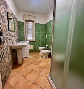 La salle de bains est pourvue d'un lavabo, de toilettes et de carrelage vert. dans l'établissement Cefalù Suite, à Cefalù